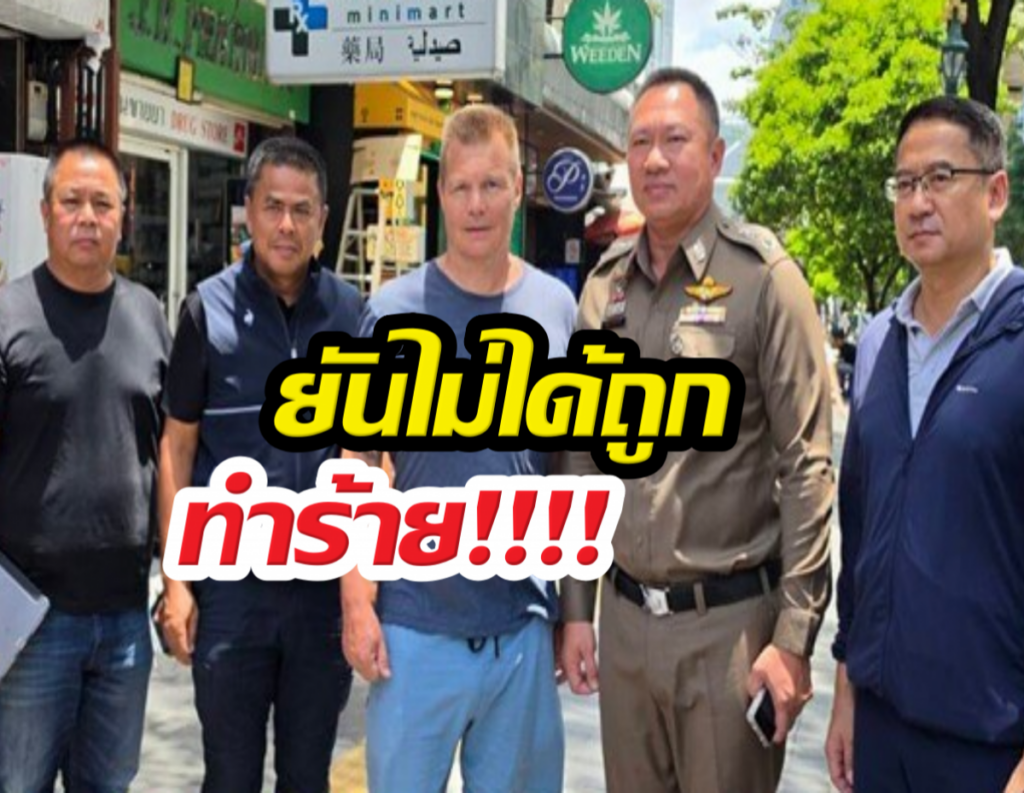 Five men posing on a city street; one wears a police uniform; bold Thai caption 'ยังไม่ได้ถุก ทำร้าย!!!!' overlays the image.