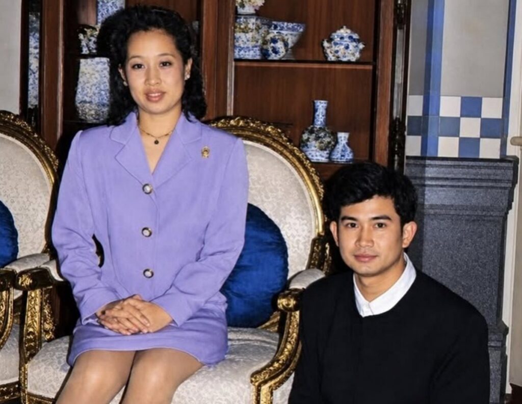 Woman in a lavender blazer sits on a gold-trimmed chair, hands folded, with a man in a dark sweater beside her in a room filled with blue-and-white porcelain.