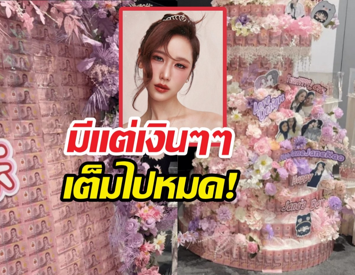 Pink floral wall with a framed portrait of a woman in the center, surrounded by pink cards and decorations, and bold Thai text overlay in red and yellow, suggesting a fan event or celebration.